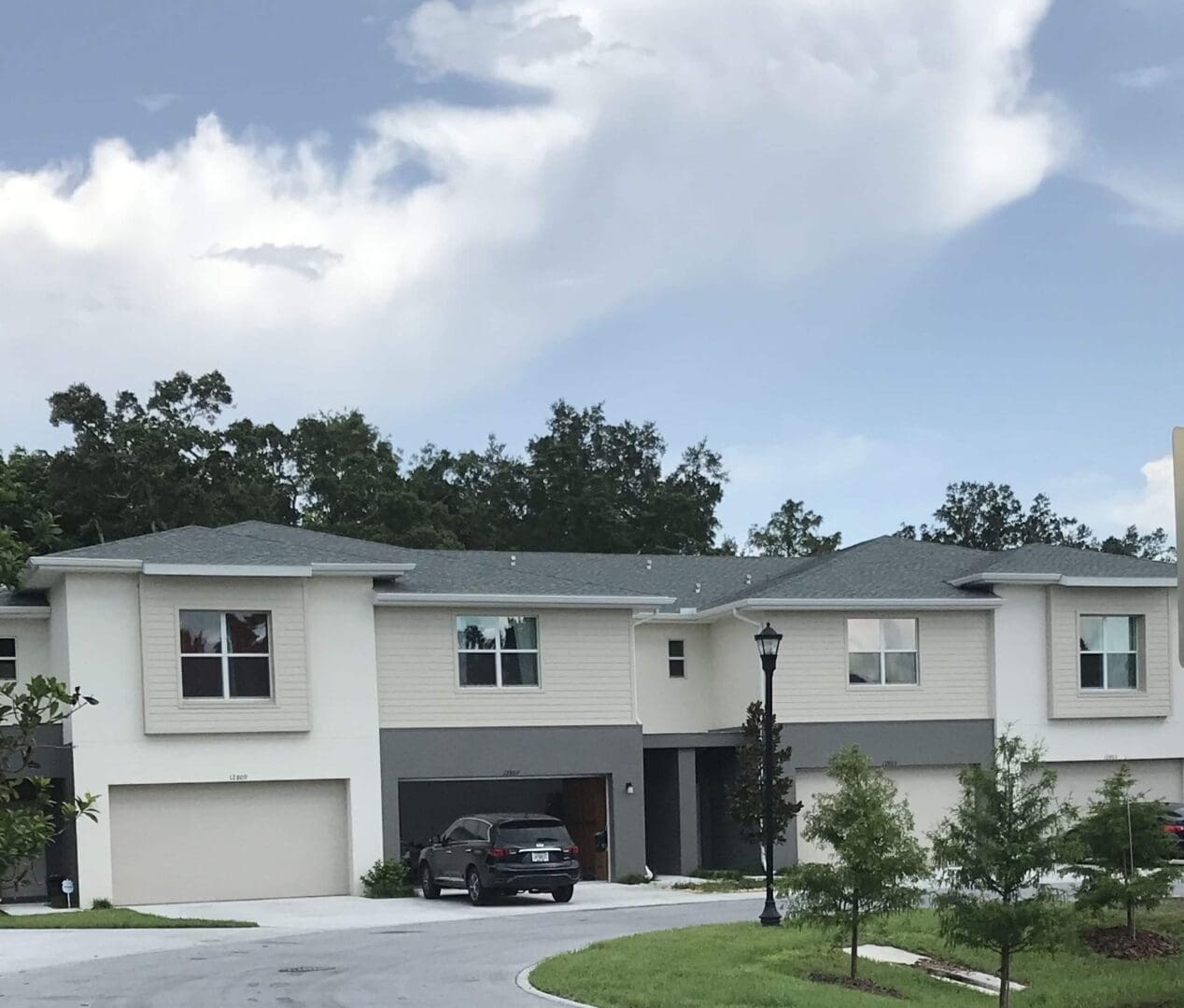 Modern townhouses with cars and trees.