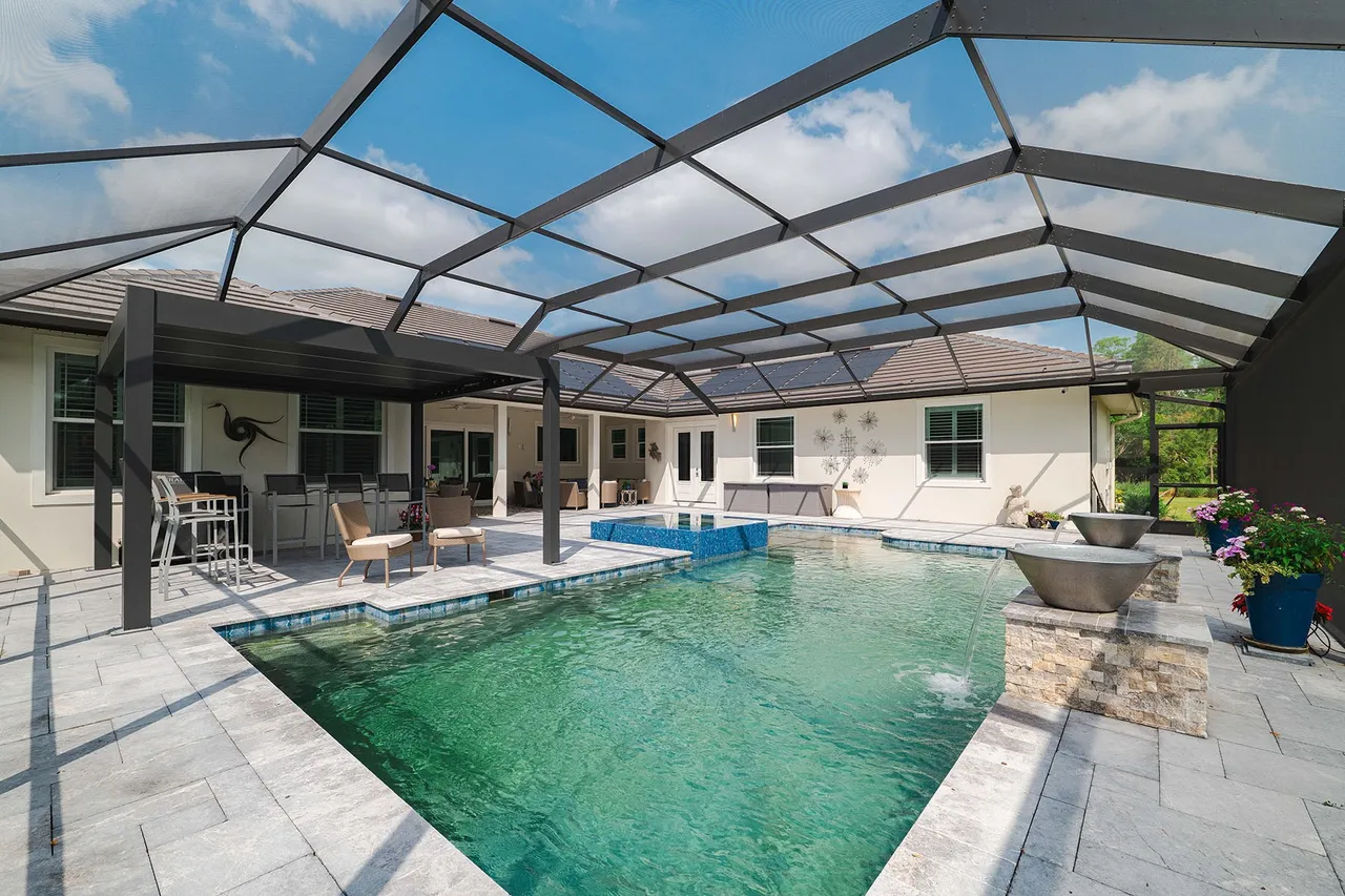 Screened backyard pool with patio furniture.
